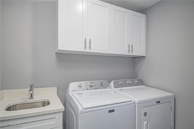 washroom featuring cabinets, sink, and washer and clothes dryer