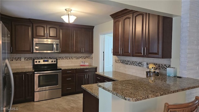 kitchen featuring tasteful backsplash, kitchen peninsula, dark brown cabinetry, and stainless steel appliances