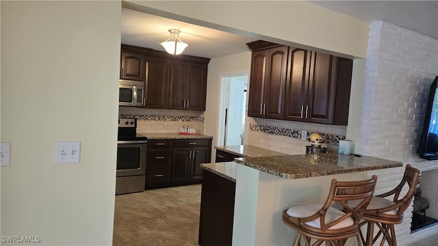 kitchen with dark brown cabinets, stainless steel appliances, and a kitchen breakfast bar