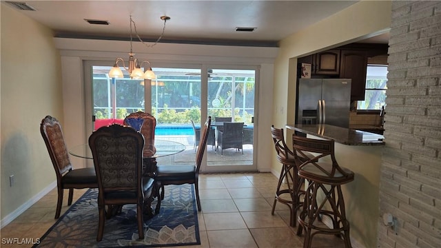 tiled dining area with a healthy amount of sunlight and a notable chandelier