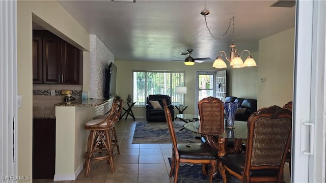 dining area featuring light tile patterned floors and ceiling fan with notable chandelier