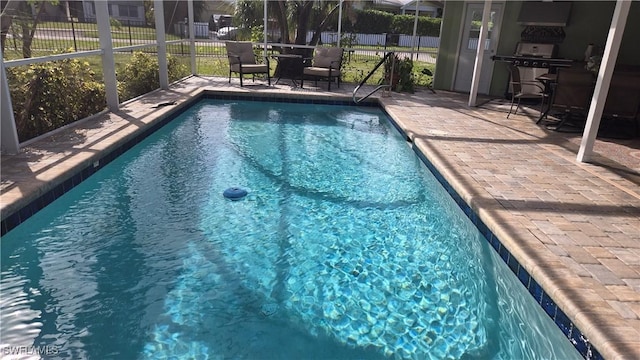 view of swimming pool featuring a patio area and a lanai