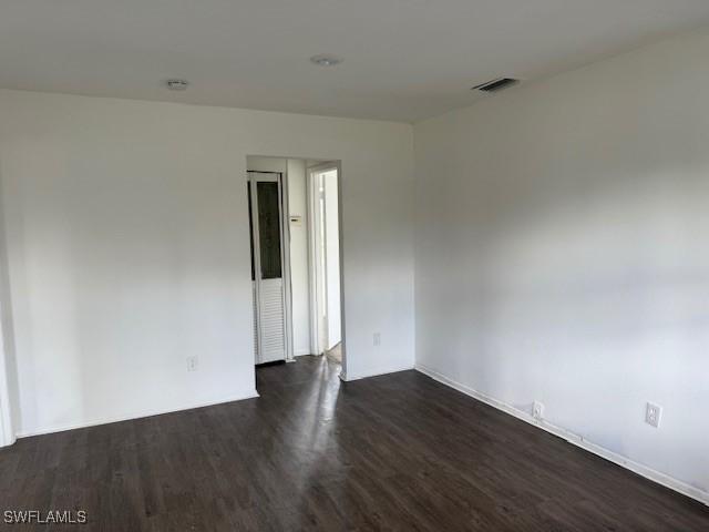 unfurnished room with dark hardwood / wood-style flooring