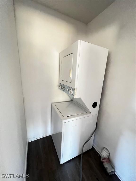 laundry area featuring stacked washer / dryer and dark wood-type flooring