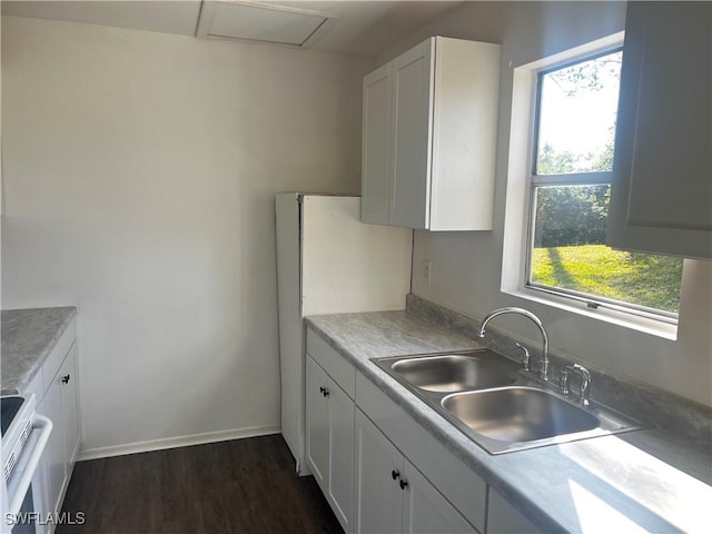 kitchen featuring dark wood-type flooring, sink, white cabinetry, and range