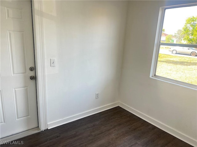 spare room with dark wood-type flooring and a wealth of natural light