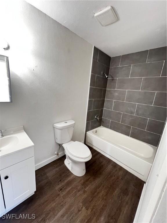 full bathroom featuring toilet, tiled shower / bath, hardwood / wood-style floors, and vanity