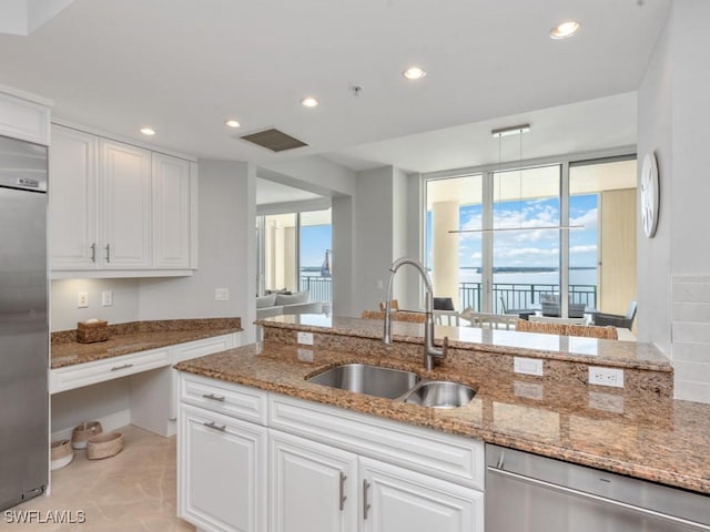 kitchen with light stone countertops, sink, white cabinetry, and stainless steel appliances