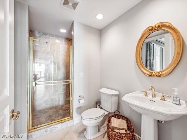 bathroom featuring toilet, a shower with shower door, and sink