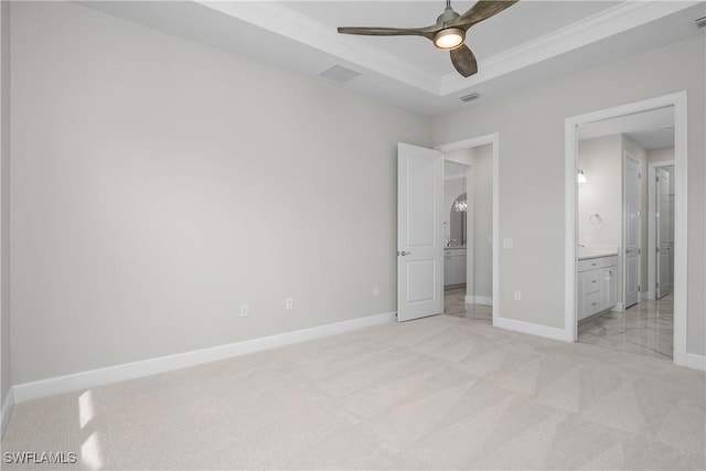 unfurnished bedroom with crown molding, ensuite bath, light colored carpet, a raised ceiling, and ceiling fan