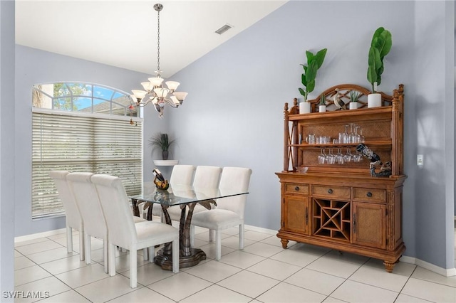 tiled dining space featuring an inviting chandelier and vaulted ceiling