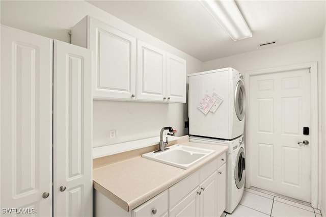 laundry room featuring cabinets, sink, stacked washer / dryer, and light tile patterned floors