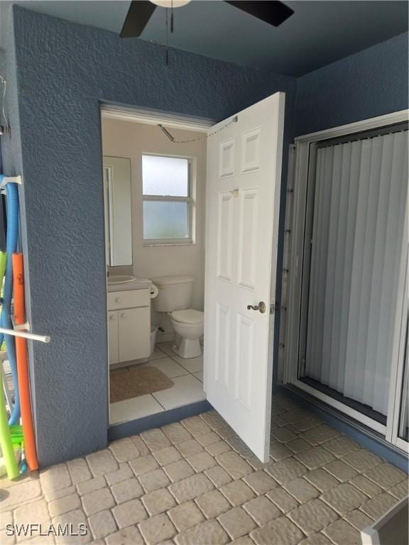 bathroom with toilet, vanity, ceiling fan, and tile patterned floors