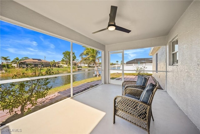 sunroom / solarium featuring a water view and ceiling fan