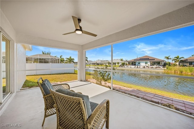 sunroom with a ceiling fan, a water view, and a residential view