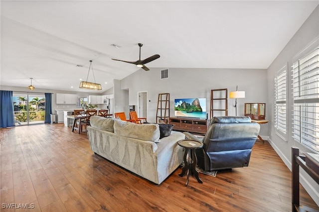 living room featuring dark wood-type flooring, a ceiling fan, visible vents, and vaulted ceiling