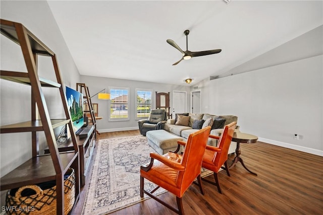 living area featuring ceiling fan, baseboards, wood finished floors, and vaulted ceiling