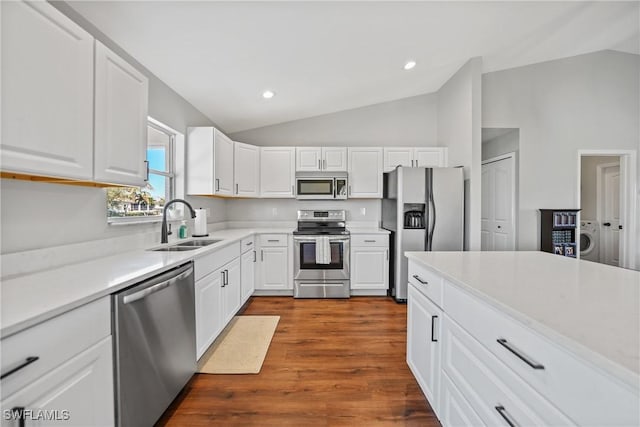 kitchen featuring light countertops, lofted ceiling, appliances with stainless steel finishes, white cabinetry, and a sink