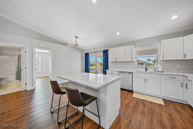 kitchen featuring a kitchen bar, visible vents, a sink, stainless steel dishwasher, and vaulted ceiling