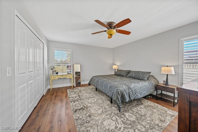 bedroom with a closet, baseboards, dark wood-type flooring, and a ceiling fan