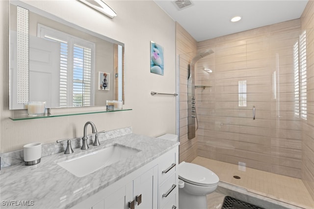 bathroom featuring tiled shower, vanity, and toilet