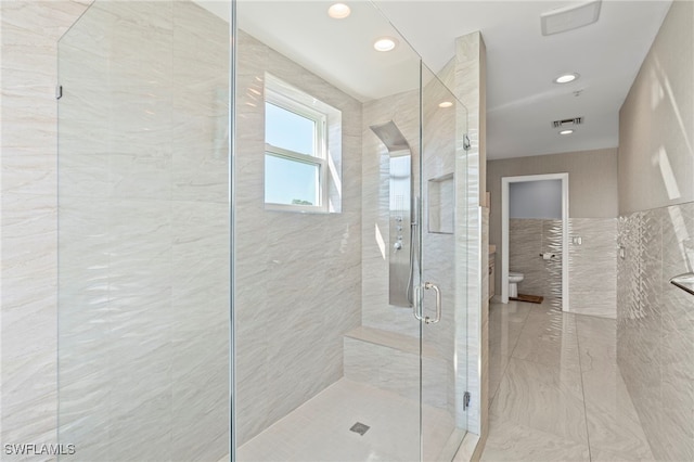 bathroom featuring a shower with shower door and toilet