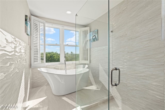 bathroom with tile walls and independent shower and bath