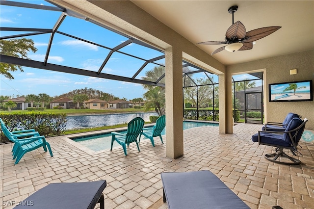 view of patio / terrace featuring glass enclosure, ceiling fan, and a water view