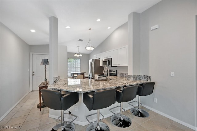 kitchen featuring kitchen peninsula, light stone countertops, decorative light fixtures, light tile patterned flooring, and white cabinetry