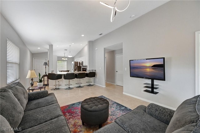 living room featuring a chandelier, sink, lofted ceiling, and light tile patterned flooring