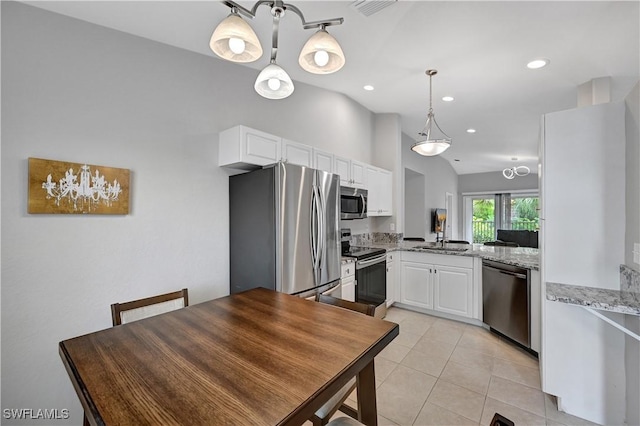 kitchen featuring white cabinets, light stone counters, stainless steel appliances, and vaulted ceiling