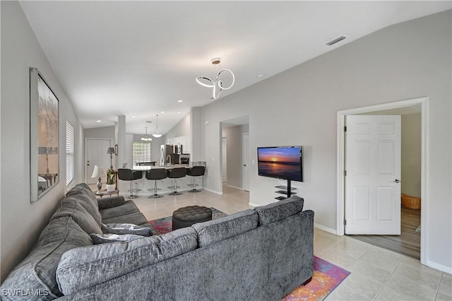 living room featuring vaulted ceiling, light tile patterned floors, and a chandelier