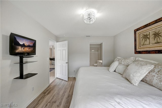 bedroom with ensuite bathroom and light hardwood / wood-style flooring