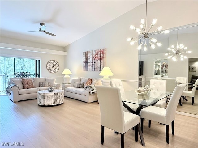 dining space with hardwood / wood-style floors, ceiling fan with notable chandelier, and lofted ceiling