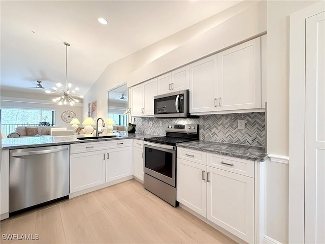 kitchen featuring white cabinets, lofted ceiling, sink, and appliances with stainless steel finishes