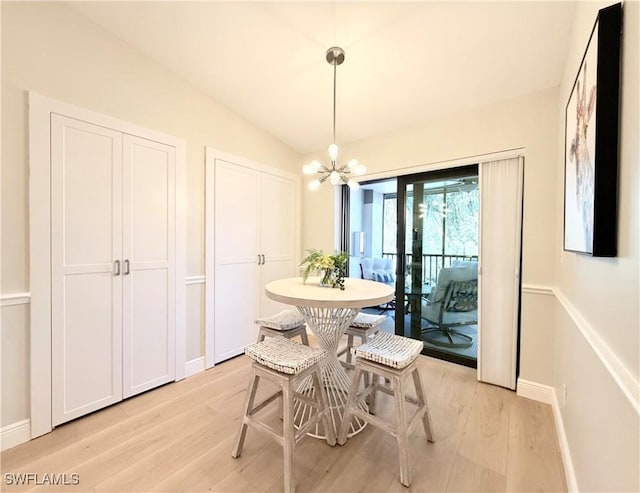 dining room with a notable chandelier, light hardwood / wood-style floors, and lofted ceiling