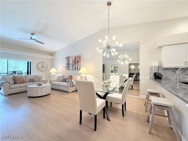 dining area with ceiling fan with notable chandelier, light wood-type flooring, lofted ceiling, and sink