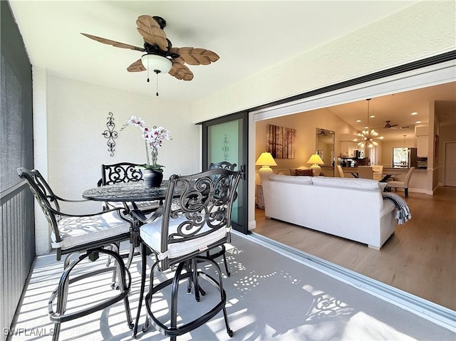 dining area featuring lofted ceiling, ceiling fan with notable chandelier, and light wood-type flooring