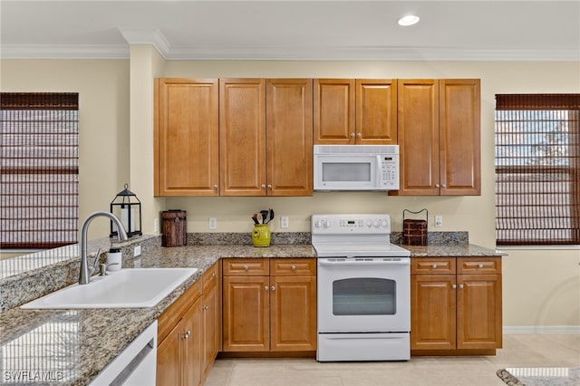 kitchen with crown molding, sink, light stone counters, and white appliances