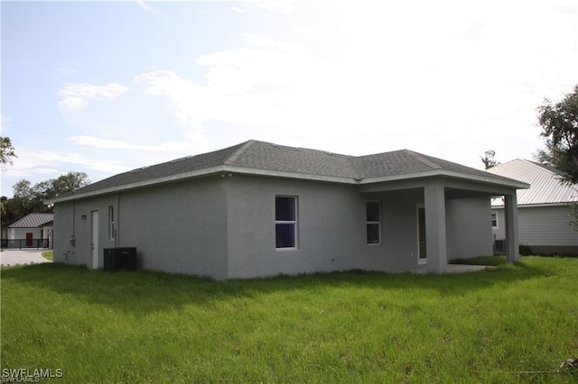 back of property featuring cooling unit and a lawn