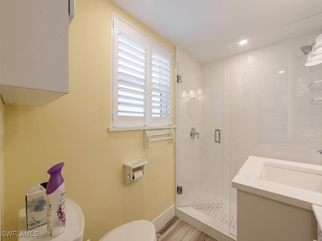 bathroom with walk in shower, hardwood / wood-style floors, vanity, and toilet