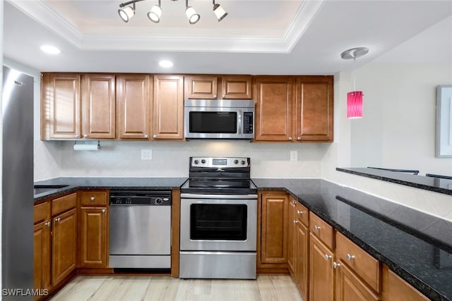 kitchen featuring a tray ceiling, backsplash, pendant lighting, and appliances with stainless steel finishes