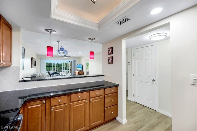 kitchen featuring ornamental molding, a tray ceiling, pendant lighting, range, and light hardwood / wood-style floors