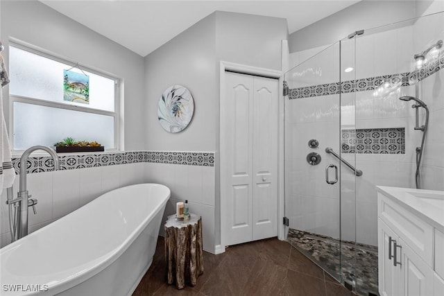 bathroom with plus walk in shower, vanity, tile patterned floors, and tile walls