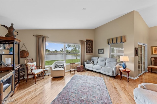 living room featuring a water view, light wood-type flooring, and vaulted ceiling