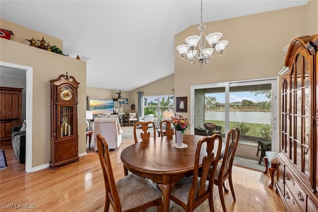 dining room with light hardwood / wood-style floors, vaulted ceiling, and a notable chandelier