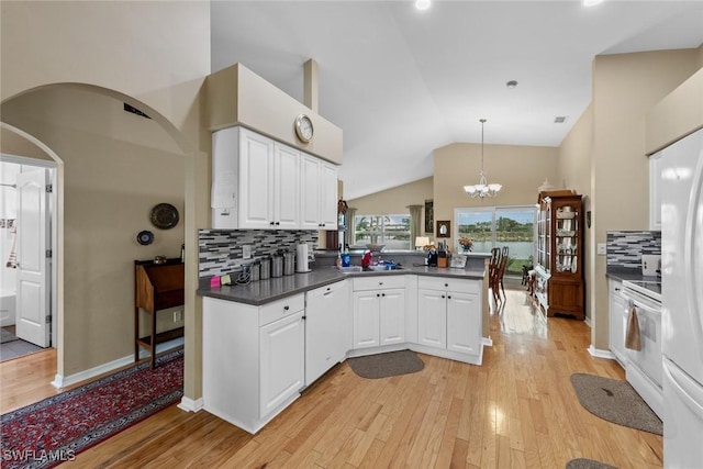 kitchen featuring kitchen peninsula, stove, backsplash, pendant lighting, and white cabinetry