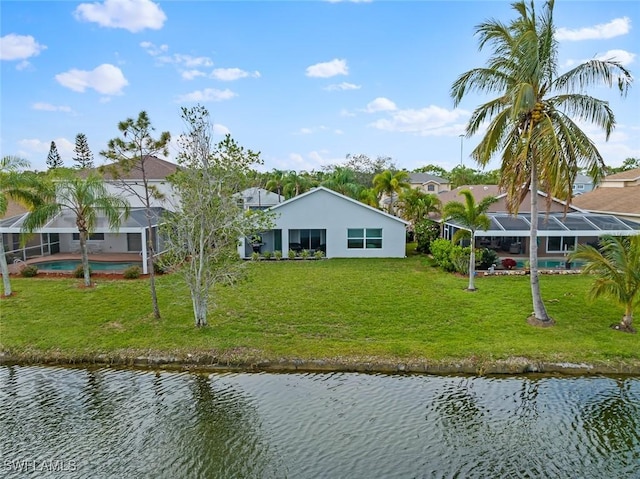 rear view of house featuring a yard, a water view, and glass enclosure