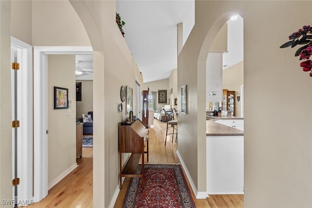 hallway with light hardwood / wood-style floors and lofted ceiling