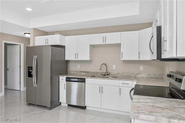 kitchen featuring white cabinets, appliances with stainless steel finishes, light stone countertops, and sink